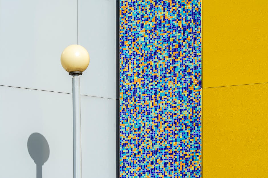 Modern building facade in Groningen featuring abstract mosaic tiles and a street lamp casting a shadow, rich in vibrant colors.