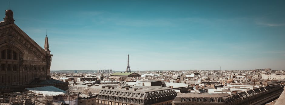 Panoramic view of Paris skyline featuring the iconic Eiffel Tower under a clear blue sky.